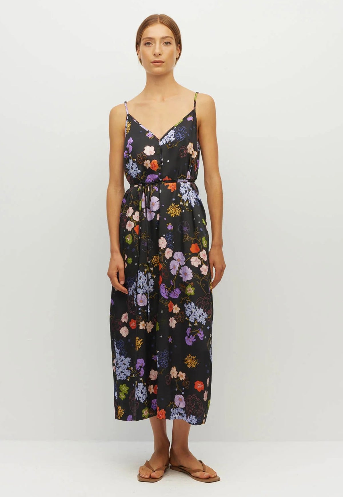 Juliette Hogan sleeveless spaghetti strap midi dress with thin straps, a V-neckline, and a multicolor floral print on a black background. With an option waist tie.