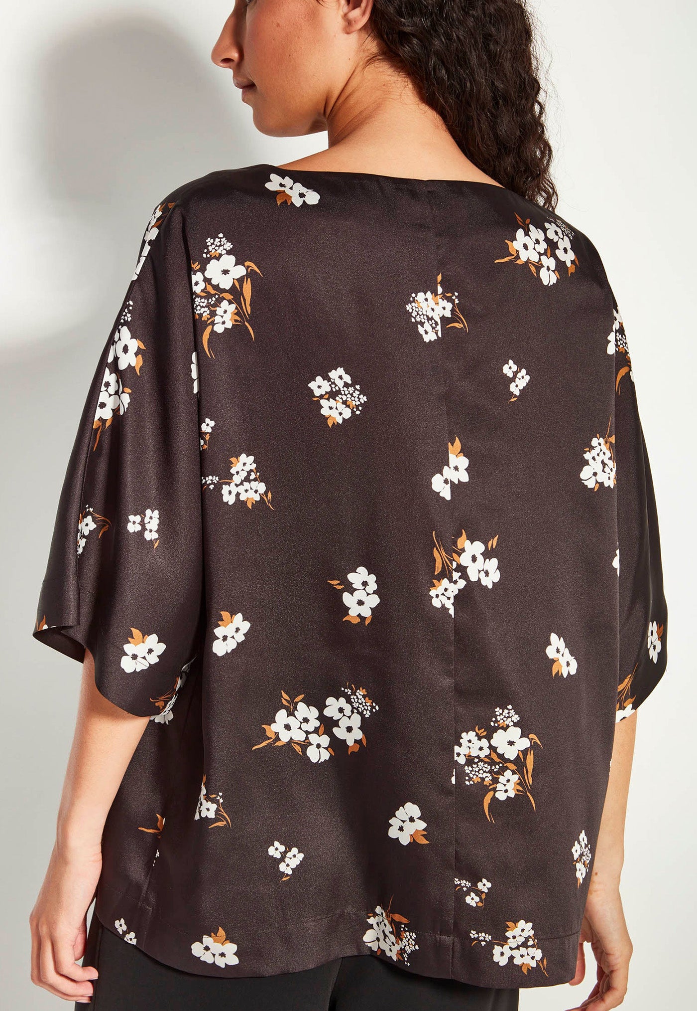 Woman wearing a black floral blouse against a plain background