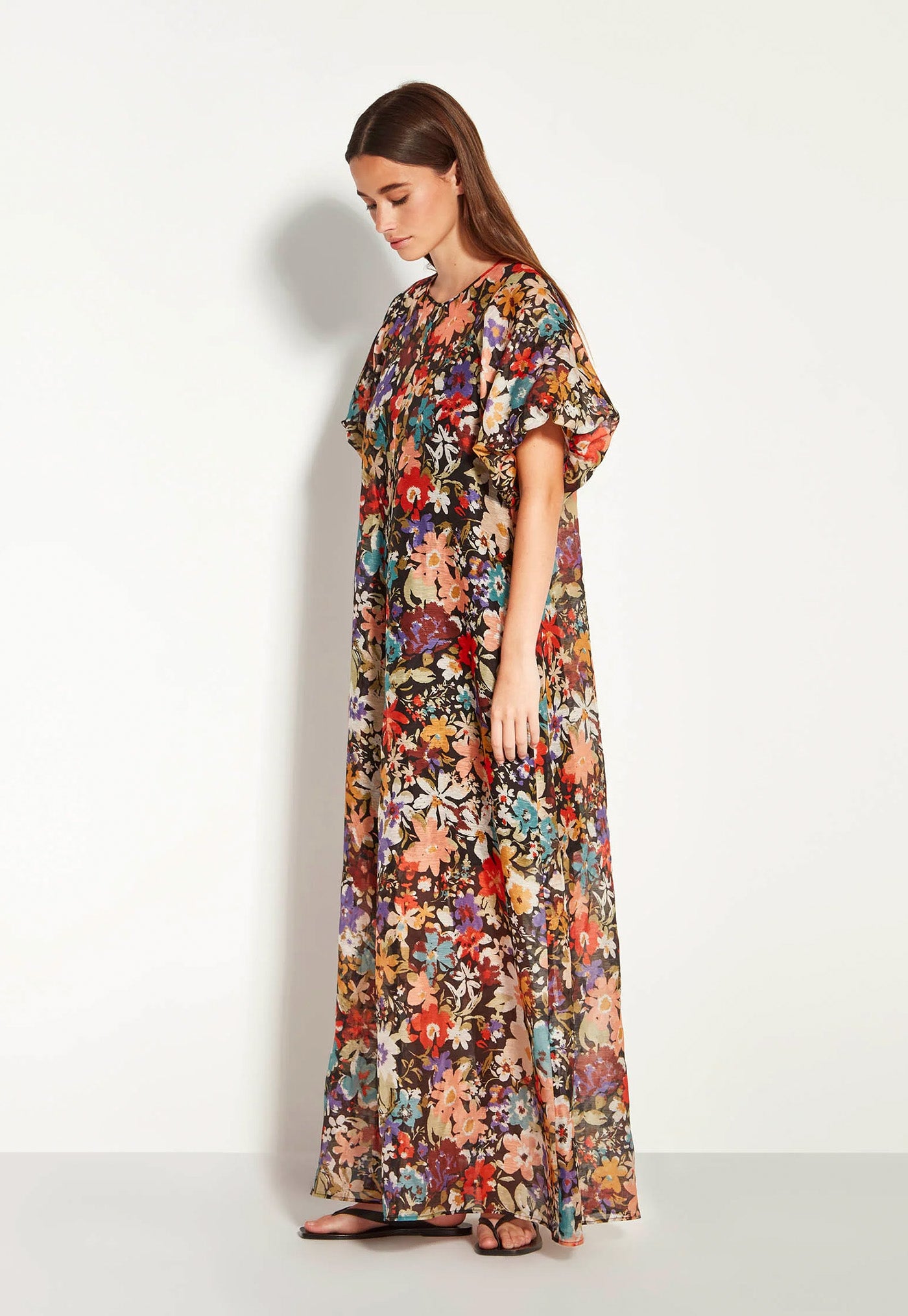 Woman wearing a long floral dress against a white background