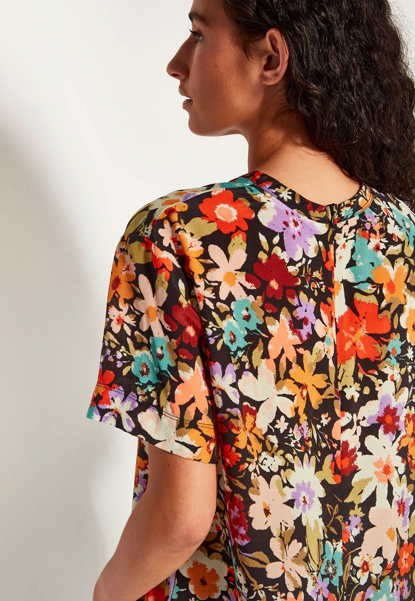 Woman wearing a colorful floral blouse against a neutral background