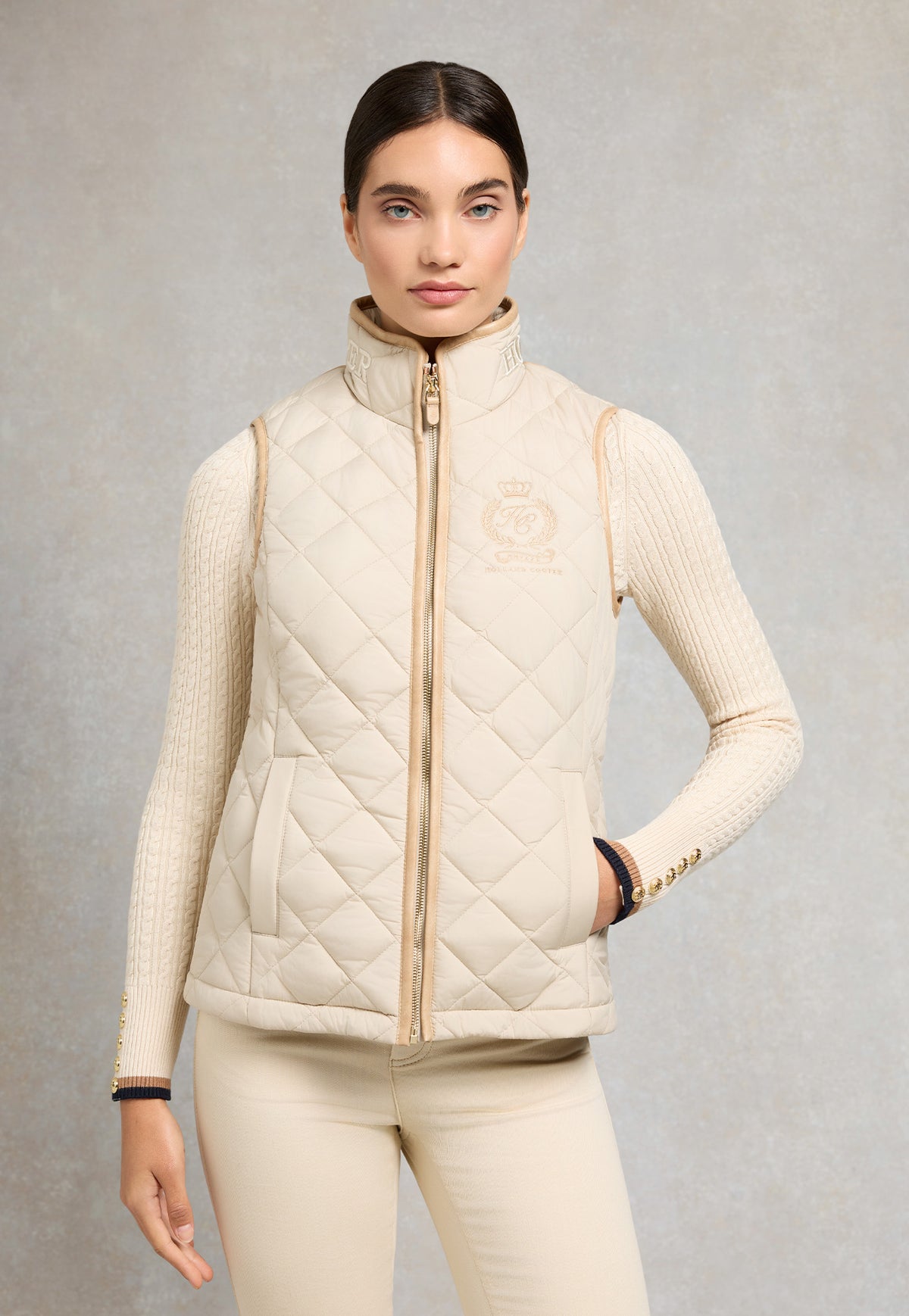 Holland Cooper Lightweight Country Gilet in Barley, light beige diamond quilted gilet with faux leather piping, front zip and crest embroidery.