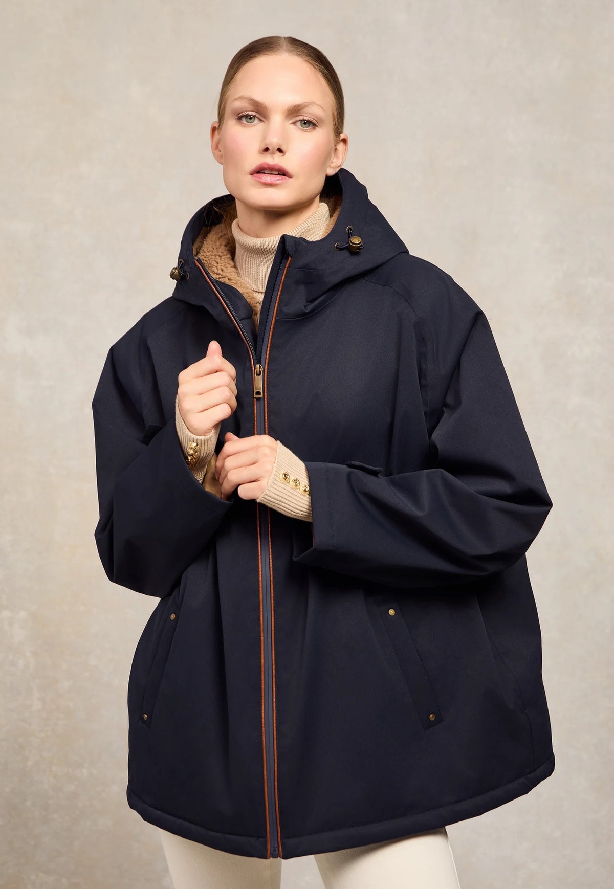 Holland Cooper One-Size Waterproof Jacket in Ink Navy, dark navy oversized mid thigh length rain jacket with borg lined hood, faux leather piping and full zip.