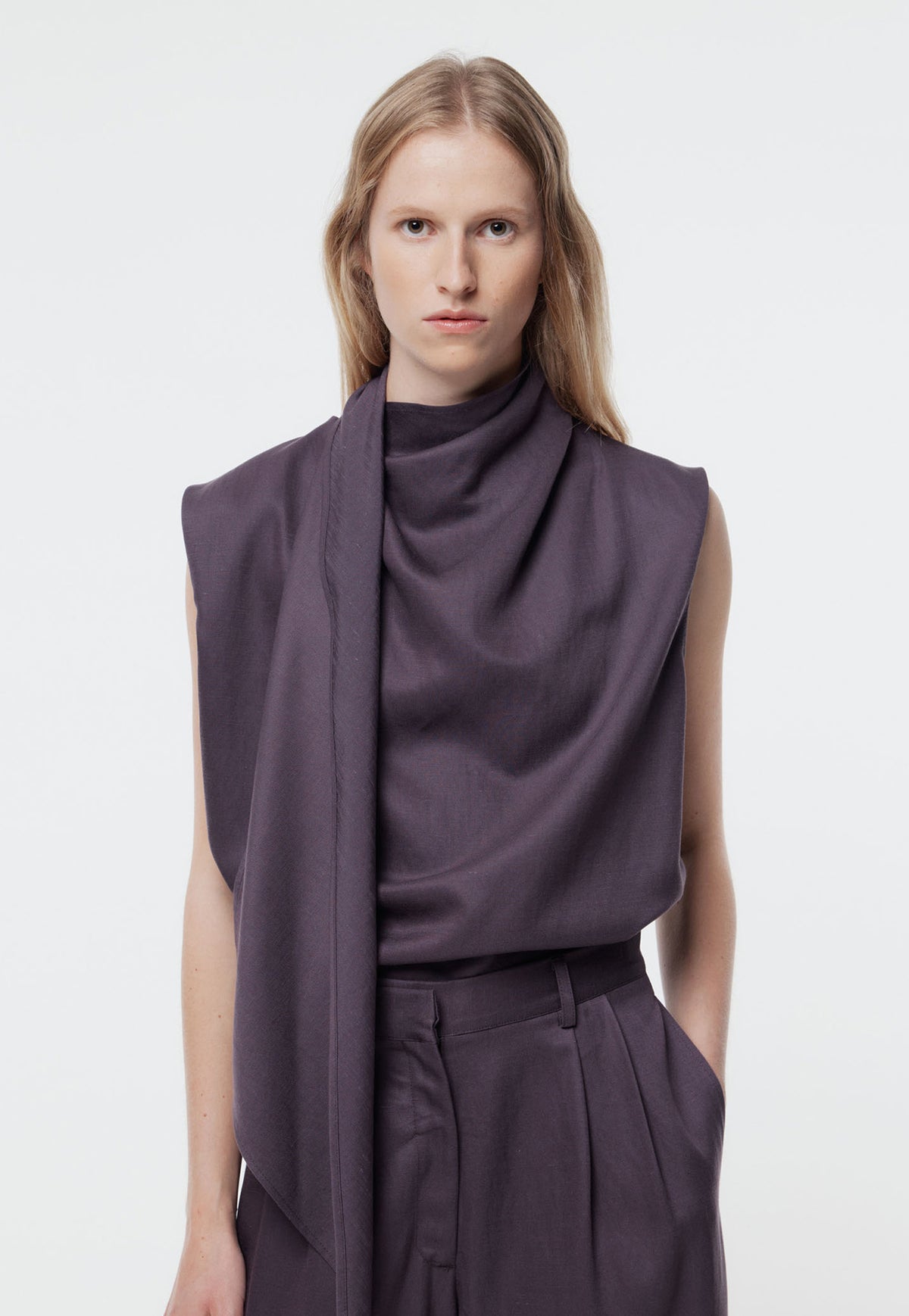 Gregory, Rosine Top in Shadow Iris. A sleeveless draped top. This elegant piece features a chic high neckline with an attached scarf detail and short sleeves, offering effortless sophistication for any occasion.