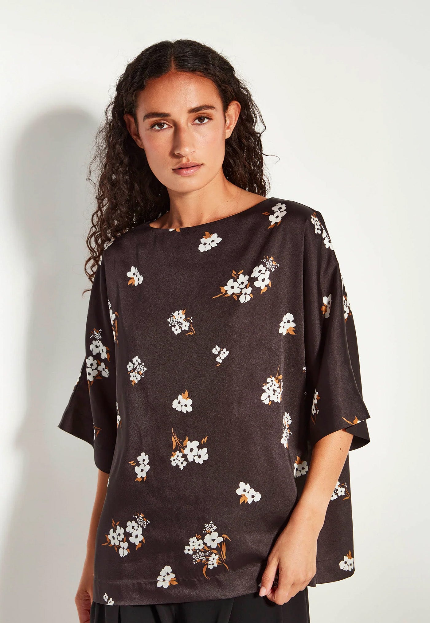 Woman wearing a black floral blouse against a white background