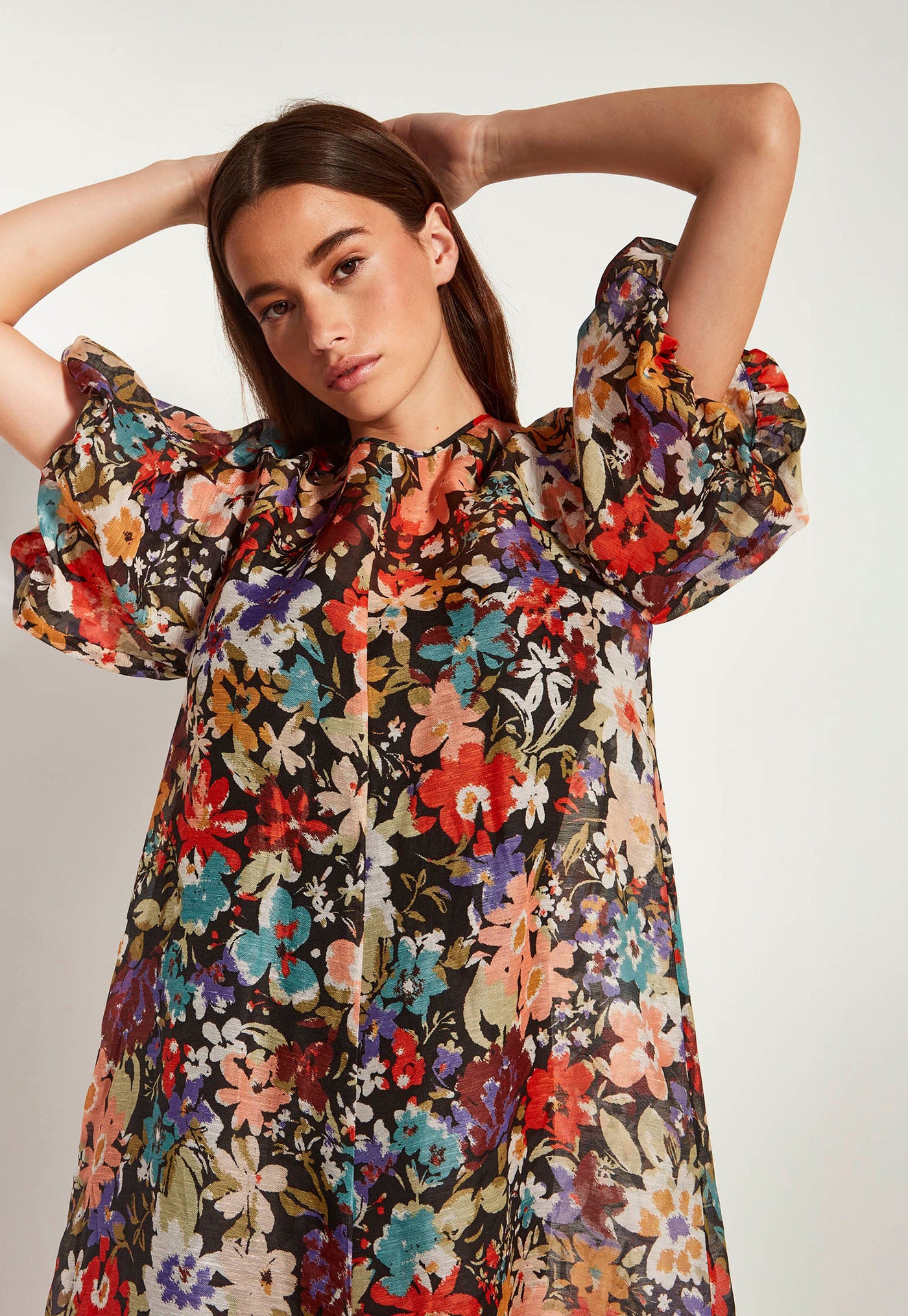 Woman wearing a colorful floral dress against a plain background