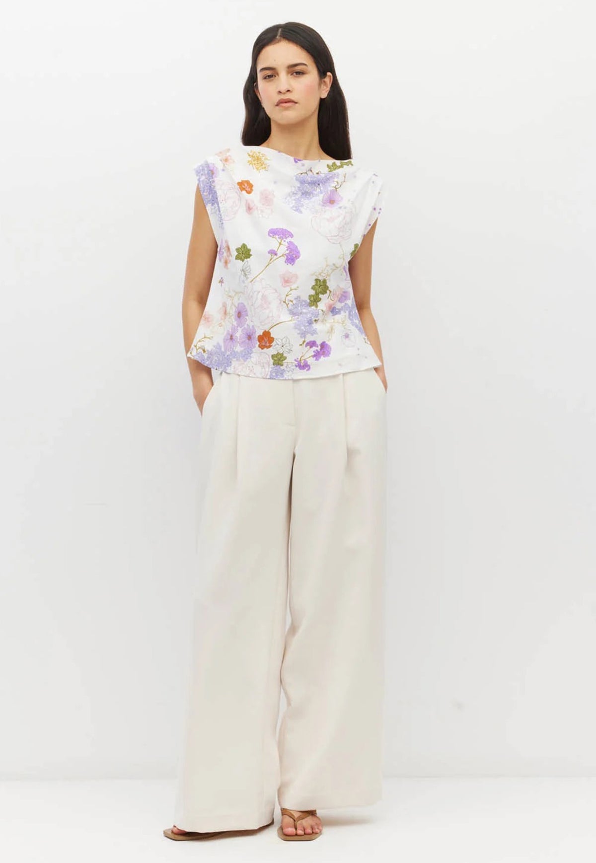 Juliette Hogan Moncaco Top. A sleeveless white top with a colorful purple, blue, red & green floral print. A wide neck draped style top.