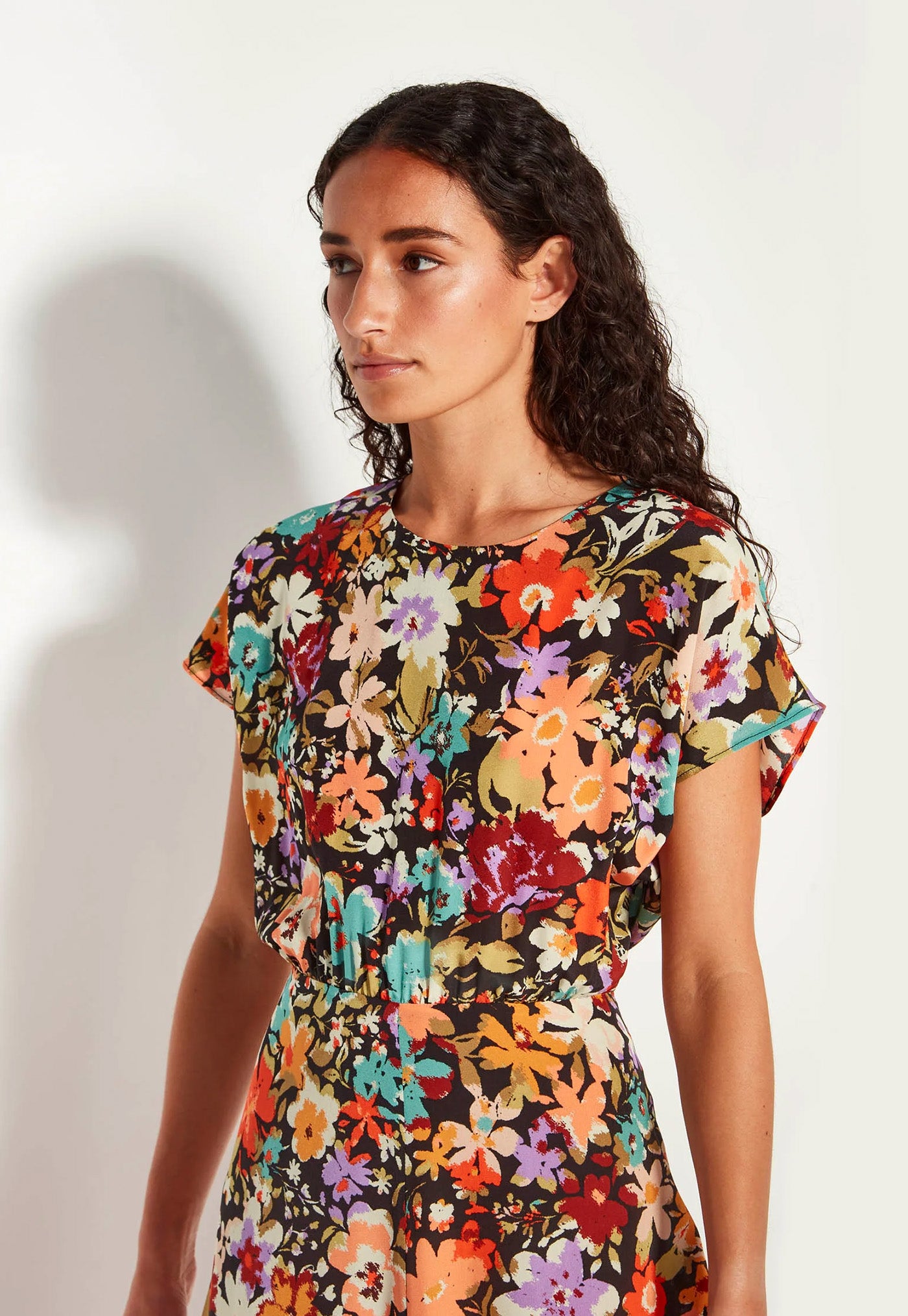 Woman wearing a colorful floral dress against a plain background