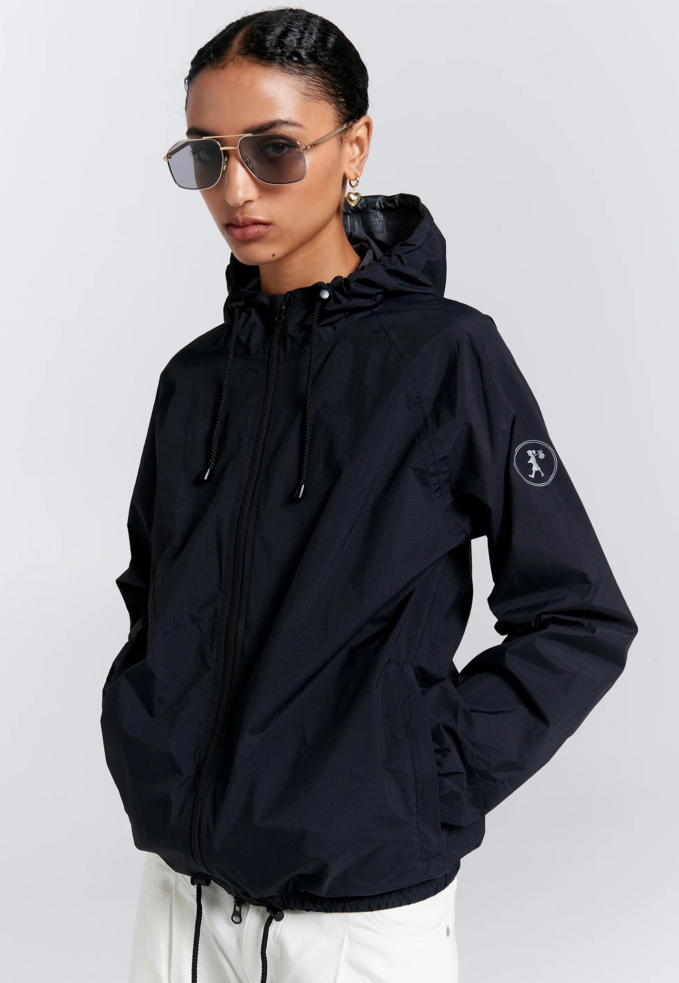 Person wearing a black hooded jacket with a brand logo on a light gray background