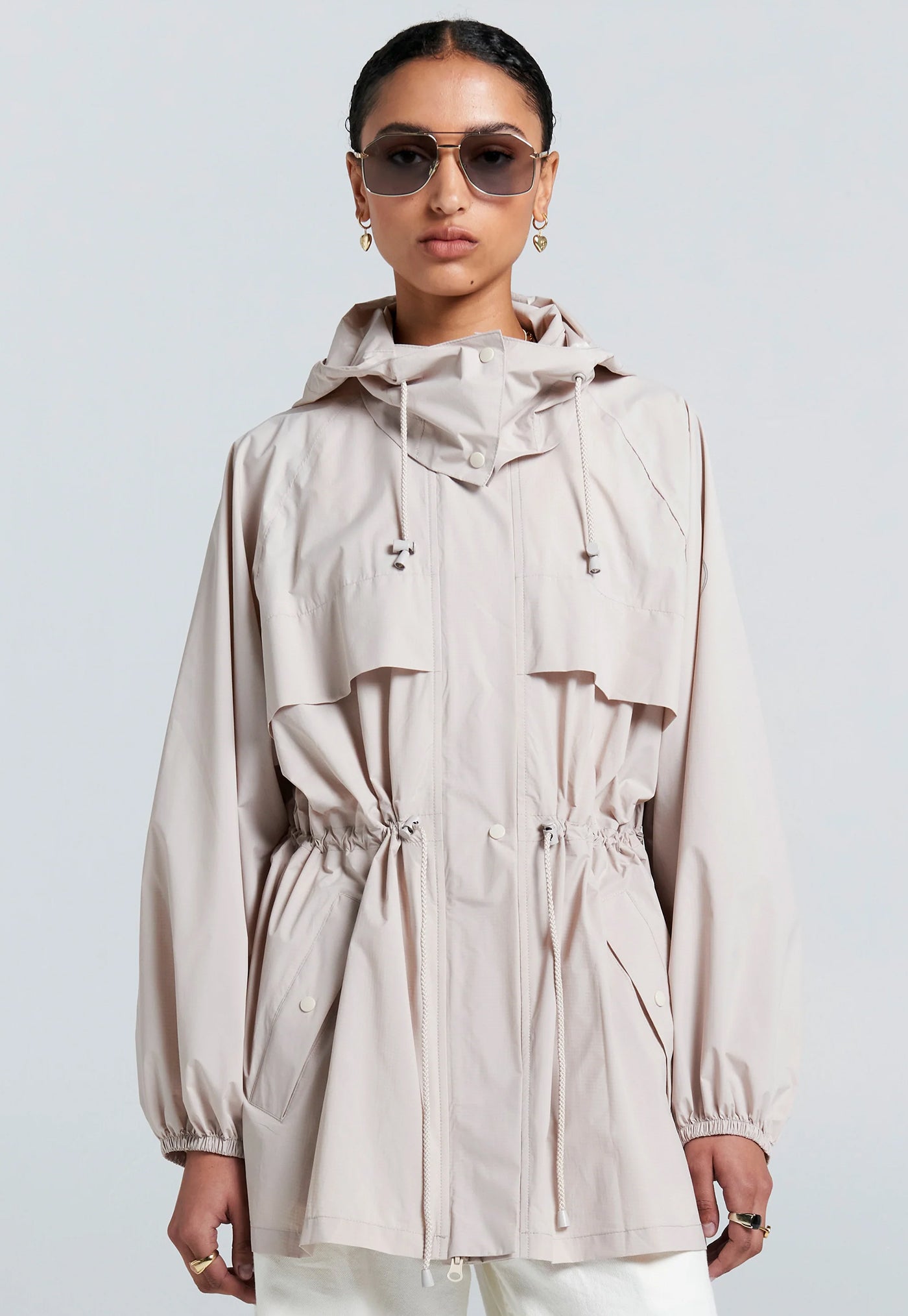 Person wearing a beige raincoat with a plain background
