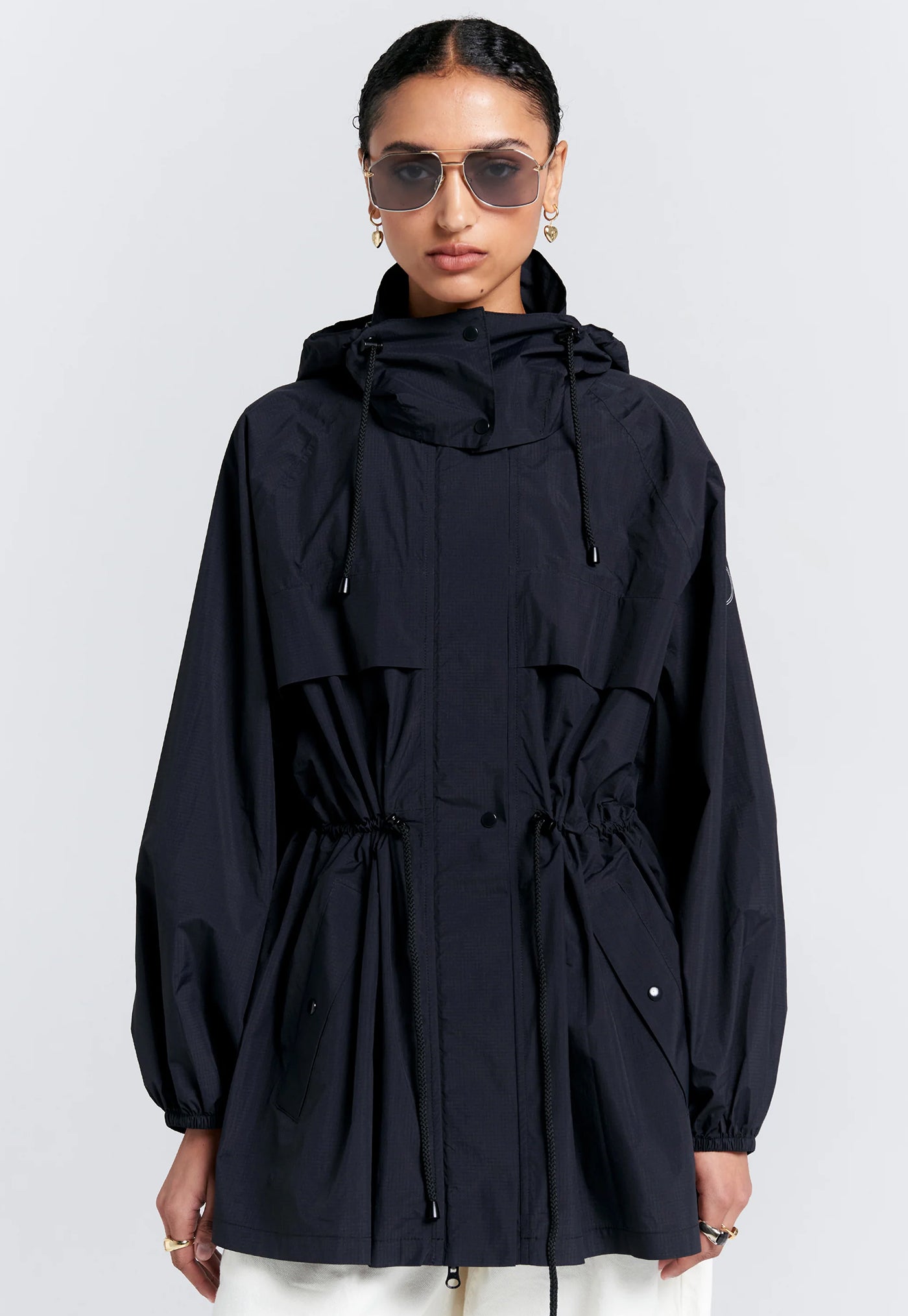 Person wearing a black hooded jacket on a white background